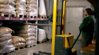 Kahve fabrikasında çalışan bir işçi palet almak için sarı çatal kullanır.