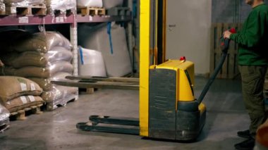 Kahve fabrikasında çalışan bir işçi palet almak için sarı çatal kullanır.