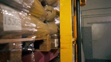 Kahve fabrikasında çalışan bir işçinin sarı bir forkliftle kahve şişesini kaldırırken yakın plan fotoğrafı.