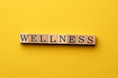 Gölgeler olmadan sarı, sıcak bir arka plan. Siyah harflerle yazılmış tahta küpler. Sağlıklı bir söz.