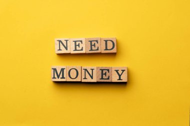 Gölgeler olmadan sarı, sıcak bir arka plan. Siyah harflerle yazılmış tahta küpler. Para lazım.