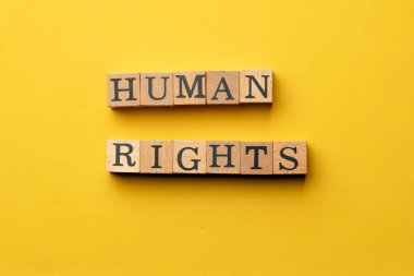 Gölgeler olmadan sarı, sıcak bir arka plan. Siyah harflerle yazılmış tahta küpler. İnsan hakları.