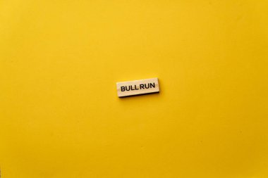 Gölgeler olmadan sarı, sıcak bir arka plan. Siyah harflerle yazılmış tahta küpler. Boğa koşusu sözcüğü.