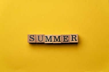 Gölgeler olmadan sarı, ılık bir arka plan. Siyah harflerle yazılmış tahta küpler. Yazı ortaya seriyor.