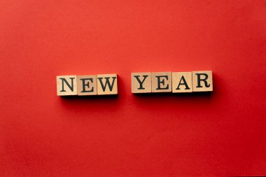 Gölgeler olmadan kırmızı, sıcak arka plan. Siyah harflerle yazılmış tahta küpler. Yeni yıl.