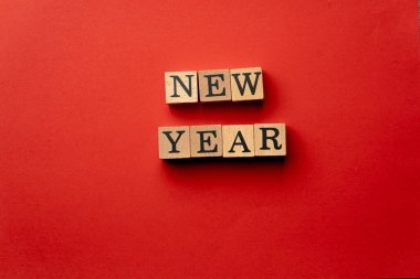 Gölgeler olmadan kırmızı, sıcak arka plan. Siyah harflerle yazılmış tahta küpler. Yeni yıl.