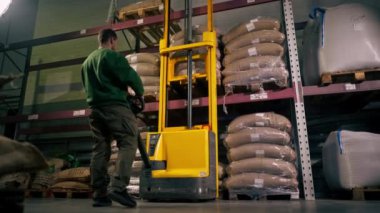 Sarı forkliftli bir kahve fabrikasında alt açı işçisi bir palet alır.