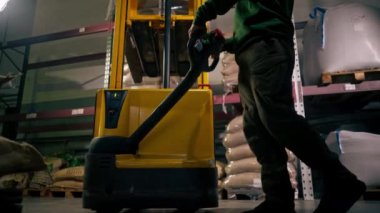 Bir kahve fabrikasında alt açı işçisi, sarı forkliftli bir adam bir palet aldı ve onu indirdi.