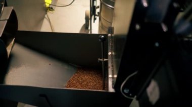 Kahve makinesinin içinde kahve çekirdeklerini sıkılaştıran bir kahve fabrikasına yakın plan.