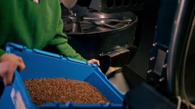Bir kahve fabrikasındaki işçi kahve kutusundan kahve kızartma mekanizmasına kahve dolduruyor.