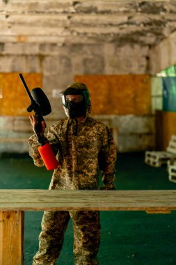 Hangarda tilt oynamanın talimatları için özel koruma ve önleme üniforması giymiş bir antrenör havalı tabancayla durur.