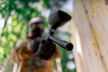 Alçak çekimde, ağaçların yakınında bir yerde tilt üniformalı bir oyuncu kırmızı balon takım kıyafeti giymiş bir tabanca tutuyor.