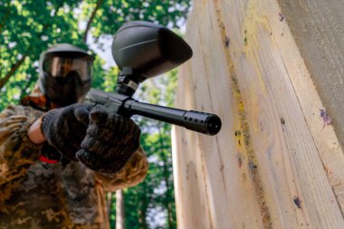 Alçak çekimde, ağaçların yakınında bir yerde tilt üniformalı bir oyuncu kırmızı balon takım kıyafeti giymiş bir tabanca tutuyor.