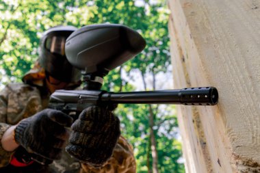 Alçak çekimde, ağaçların yakınında bir yerde tilt üniformalı bir oyuncu kırmızı balon takım kıyafeti giymiş bir tabanca tutuyor.