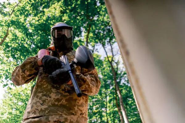 Ağaçların yakınındaki vahşi doğada tilt üniformalı bir oyuncu kırmızı balon takım kıyafetleriyle bir tabanca tutuyor.