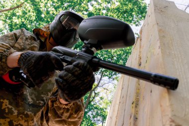 Alçak çekimde, ağaçların yakınında bir yerde tilt üniformalı bir oyuncu kırmızı balon takım kıyafeti giymiş bir tabanca tutuyor.