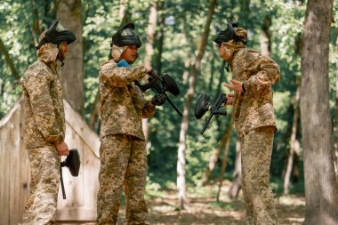 Ormanda, sahanın ortasında tilt oyuncuları üniformalı ve maskeli adamlardan duygusal açıklamalar kazanmak için oyunu nasıl oynayacaklarını tartışıyor ve el kol hareketi yapıyorlar.