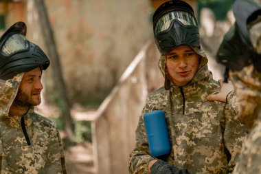 Ormanda, sahanın ortasında tilt oyuncuları üniformalı ve maskeli adamlardan duygusal açıklamalar kazanmak için oyunu nasıl oynayacaklarını tartışıyor ve el kol hareketi yapıyorlar.