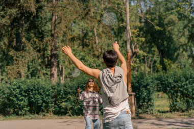 Dışarıda ağaçlarla dolu bir parkta esmer bir adamla esmer bir kız bambinton oynuyorlar. En iyi arkadaşlar birlikte rahatlıyor. Kız servis yapıyor.