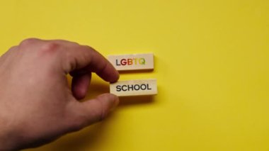 Gölgeleri olmayan sarı, sıcak bir arka plan. Erkek eli, LGBT okulunu renklendiren ahşap küplerle kapladı.