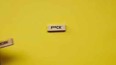 Yellow warm background without shadows the male hand laid wooden cubes with colored words laid out the fuck work