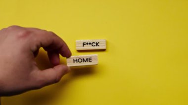 Yellow warm background without shadows the male hand laid wooden cubes with colored words laid out the fuck home