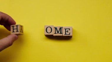 Gölgeleri olmayan sarı, sıcak bir arka plan. Erkek eli, evi renkli kelimelerle süsleyen ahşap küpler seriyordu.