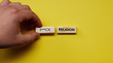 Yellow warm background without shadows the male hand laid wooden cubes with colored words laid out the fuck religion