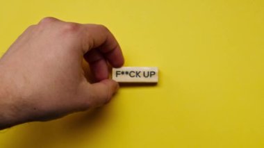 Yellow warm background without shadows the male hand laid wooden cubes with colored words laid out the fuck