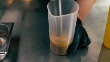 Profesyonel bir mutfak aşçısı salata sosu hazırlar. Karıştırıcıyla döver.