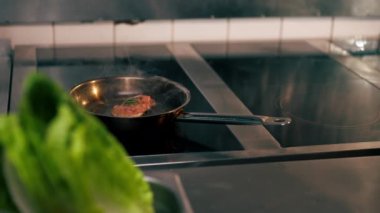 Profesyonel bir mutfakta bir parça tavuk fileto küçük bir tavada kızarır.