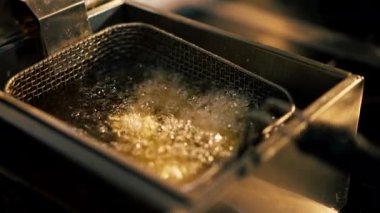 Profesyonel bir mutfakta yakın plan çekimde tavuk kanatlarını fritözde kızartıyorum.