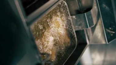 Profesyonel bir mutfakta yakın plan çekimde tavuk kanatlarını fritözde kızartıyorum.