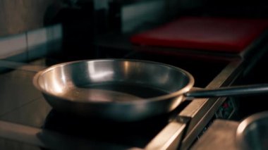 Profesyonel mutfakta yakın plan çekimde şef çantası kızartma tavasında koyu bir şekilde süzülür.