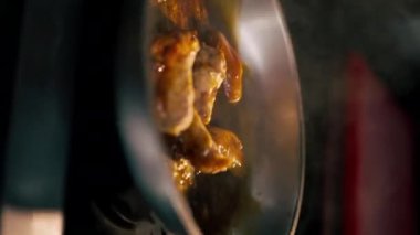Profesyonel bir mutfağın tavasında sosta kızartılmış tavuk kanatları videosu.