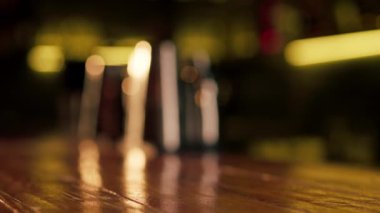 Ahşap bir bar masasına yakın plan bir adam bir bardak light bira tutuyor.