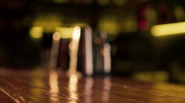 Ahşap bir bar masasına yakın plan bir adam bir bardak light bira tutuyor.