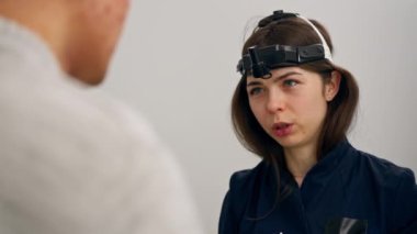 Klinikte yakın plan mavi kulaklı genç bir doktor konsültasyon yapıyor.