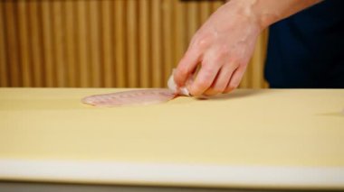 Japon restoranına yakın mavi üniformalı bir şef sarı tahtada suşi için balık keser.