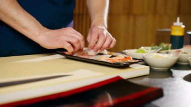 Japon restoranına yakın çekim yapan şef, tabağa çiğ balık parçaları serer.