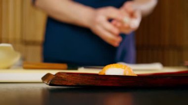 Japon restoranına yakın çekim yapan şef, tabağa çiğ balık parçaları serer.