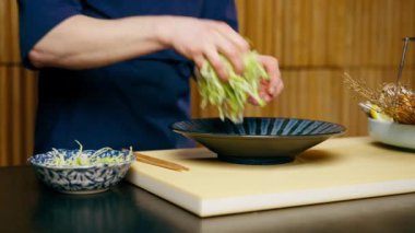 Japon restoranına yakın çekim yapan mavi elbiseli bir şef pahalı bir tabak deniz ürünü hazırlar.