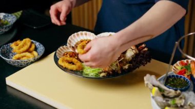 Japon restoranına yakın çekim yapan mavi elbiseli bir şef pahalı bir tabak deniz ürünü hazırlar.
