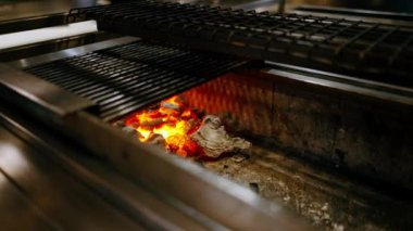 Japon restoranının kompakt masa üstü ızgarasında yüksek sıcaklıktaki kömürleri pişirmek için yakın plan.
