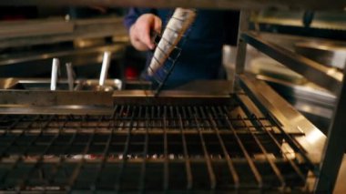 Bir Japon restoranında mavi üniformalı bir şef mutfaktaki ızgarada balık kızartıyor.