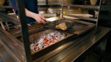 Japon restoranına yakın mavi üniformalı bir şef mutfaktaki ızgarada balık kızartacak.