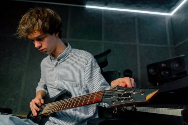 Kayıt odasındaki ekipmanda müziğin sesi yakışıklı genç bir adam gitarı akort ediyor, telleri koparıyor ve istenen ses tonunu seçiyor.