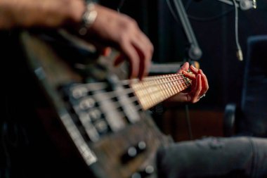 Yakın çekim bir kayıt odası ekipmanı sakallı ve dövmeli yakışıklı bir adam elektro gitar çalıyor teller doğru notayı seçiyor