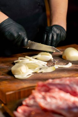 Lokantada yakın bir yerde, merkez salonda bir kaburga barda siyah eldivenli bir şef büyük bir parça et hazırlıyor.