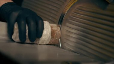 Merkezdeki bir kaburga barında, siyah eldivenli bir şefin sarı ışıklarıyla profesyonel bir dilimleme makinesinde sosis kestiği bir restoranda.